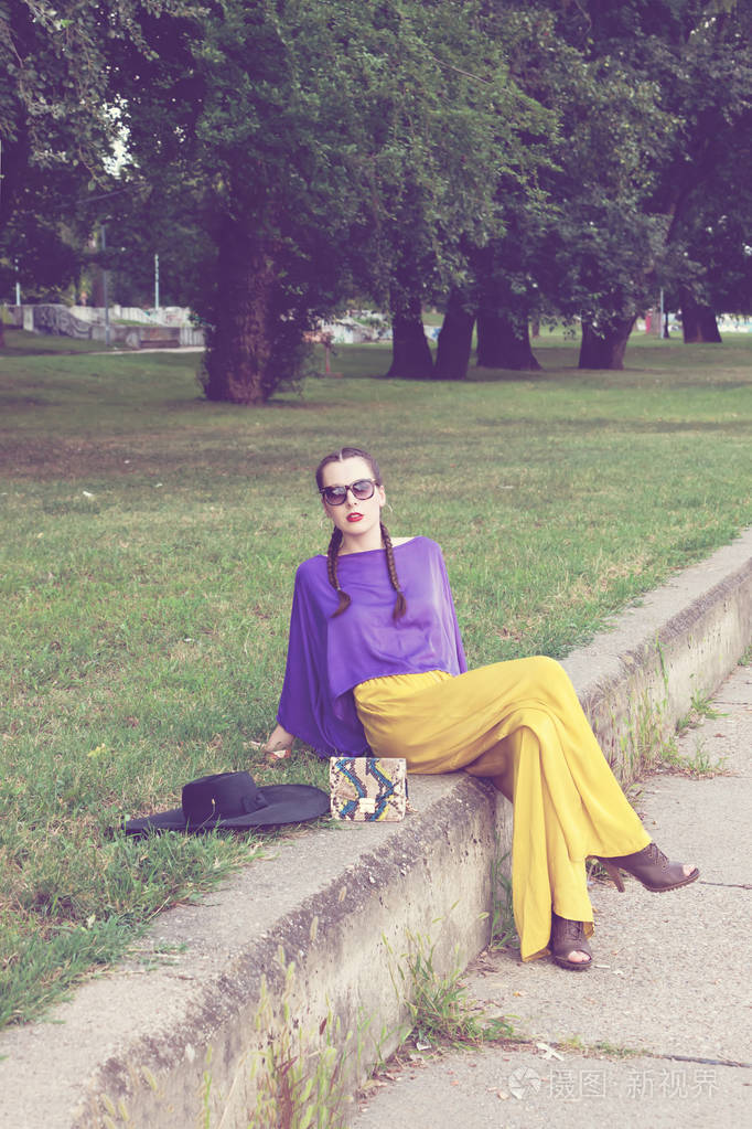 坐在公园里摆姿势拍照的漂亮年轻女子时装模特