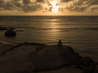 日落或日出时在海滩上练习瑜伽的人。 股票形象的景观天堂热带岛屿海滩和一个人练习瑜伽和冥想海滩在早晨日出。 健康的生活方式