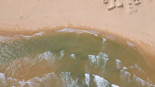 鸟瞰美丽的海浪沙从无人机。 股票图像海水海面沙。 顶部看到绿松石波，清澈的水面纹理。 顶级景观，令人惊叹的自然海滩背景