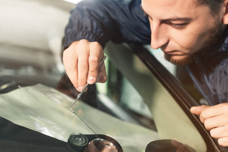 关闭汽车玻璃工工人修理和修理汽车维修站车库的挡风玻璃或挡风玻璃