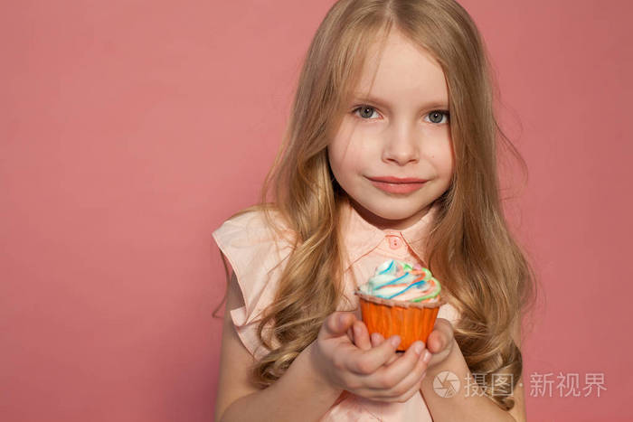 小女孩在手拿着一个甜蜜的纸杯蛋糕糖果