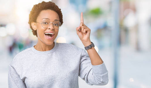 年轻美丽的非裔美国妇女戴着眼镜，在孤立的背景上指点着成功的想法。 退出并快乐。 一号。