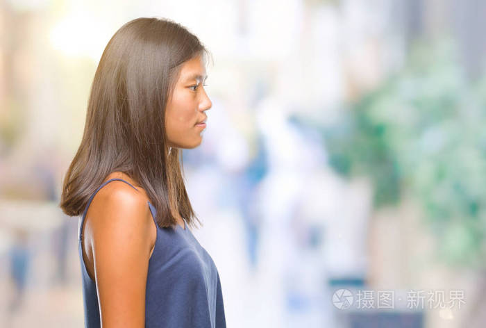 年轻的亚洲女人在孤立的背景下,看着侧面放松的轮廓姿势,自然的脸