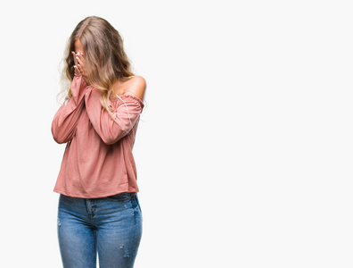 美丽的年轻金发女人在孤立的背景上,悲伤的表情覆盖着脸,双手哭泣.