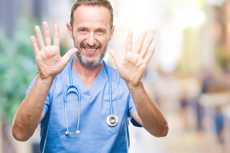 中年老年医生男子穿着医疗制服，在孤立的背景上，显示和举着十个手指，同时微笑自信和快乐。