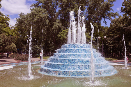 城市喷泉。 在炎热的夏天，城市公园里的喷泉。 美丽的城市喷泉里的水滴和明亮的水溅。 白天城市喷泉中波光粼粼的水流