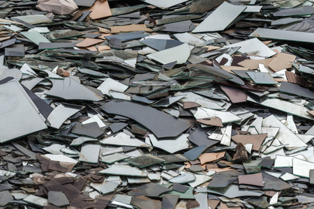 垃圾场里有一大堆破碎的玻璃碎片。 大件镜面和玻璃在垃圾工业废物和玻璃加工中的应用。 晨光中的一束镜子碎片