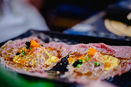 在日本餐厅的黑盘上，选择了一套带有鱼罗和托比科的烤瓦尤牛肉寿司。 日本食物瓦圭牛肉鱼
