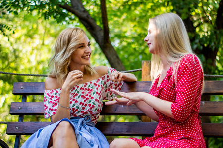 两个迷人的金发女朋友在公园里聊天和拥抱.
