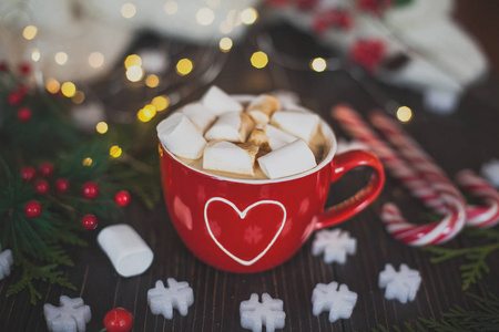 美味的自制热巧克力和棉花糖在一个大红色的杯子里。 背景上的圣诞装饰。景深较浅