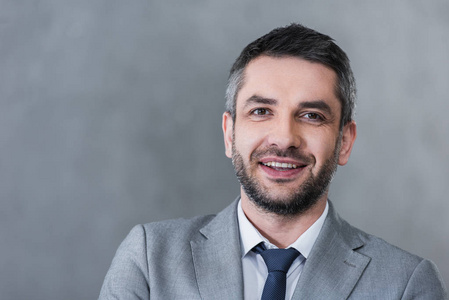 一幅自信英俊的商人的肖像,穿着正式服装,对着镜头微笑,灰色照片