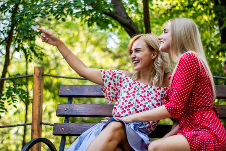 姐妹们在一起玩两个迷人的金发女朋友在公园里聊天和拥抱.
