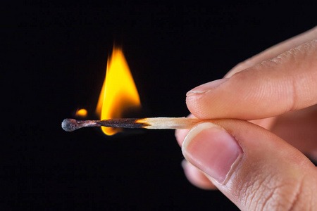 燃烧火柴棒在手上的黑色孤立的背景.照片