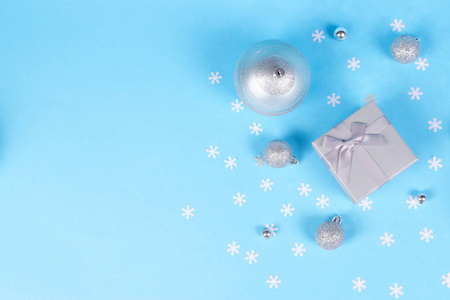美丽的银礼品盒的组成与可爱的丝质蝴蝶结和大和小闪亮的圣诞包在蓝色背景装饰雪花纸屑与复制空间。