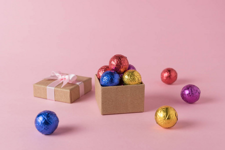 彩色糖果和礼品盒在粉红色背景上的创意布局。 最小的假期概念。