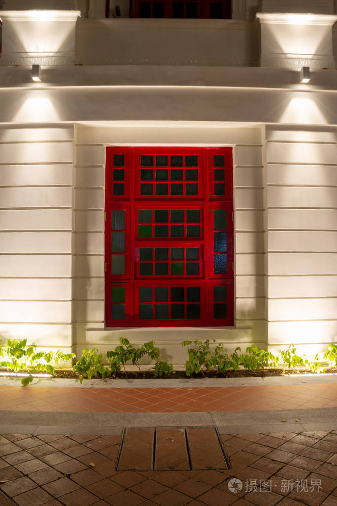 夜间白色建筑上的红色窗框