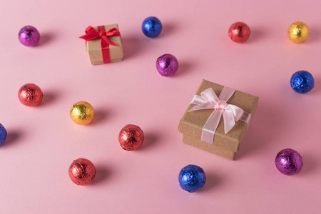 彩色糖果和礼品盒在粉红色背景上的创意布局。 最小的假期概念。