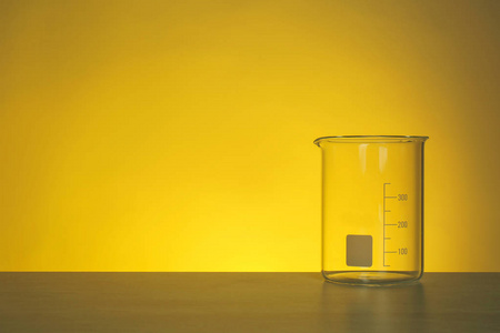桌子上的空烧杯在彩色背景下。 化学实验室玻璃制品