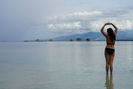 穿比基尼的女人在海滩上举起双手摆姿势的后视镜