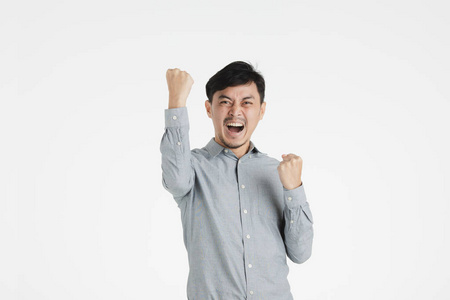 半长的摄影棚里,一位身穿灰色衬衫的兴奋的亚洲年轻