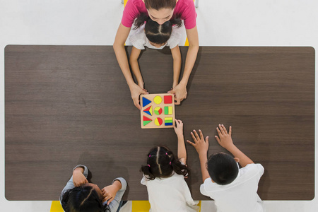 几何积木亚洲教师的平躺镜头与亚洲学生一起玩几何积木玩具,概念为
