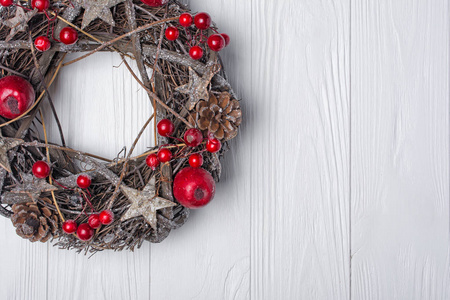 从树枝星星和松果上观看传统圣诞花环，红色装饰，如苹果和浆果，白色木制背景，带有复制空间