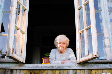老妇人从一所乡村房子的窗户看。