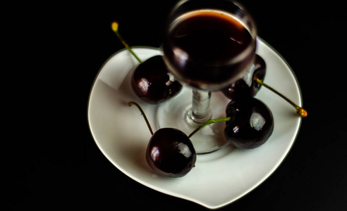 在酒吧的桌子上放着樱桃利口酒和多汁的成熟樱桃，一份优雅的甜饮料，在餐馆里是一种传统的饮料