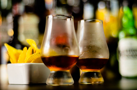 一杯威士忌加冰块和咸点心在酒吧聚会的背景上