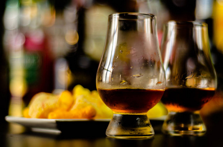 一杯威士忌加冰块和咸点心在酒吧聚会的背景上