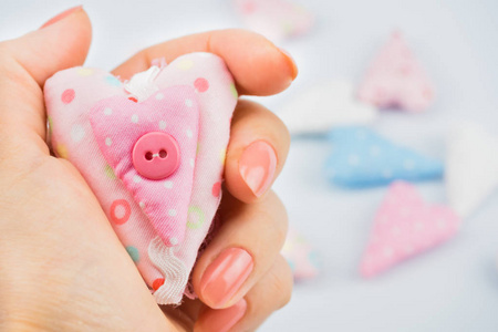 s hand close up, holding a pink fabric heart. White background i