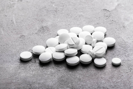 灰色纹理背景上的白色药丸照片