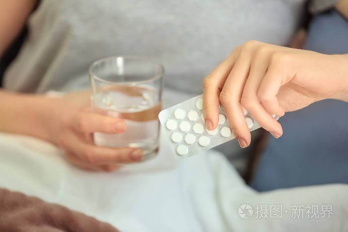 年轻女子在床上吃药照片-正版商用图片16dcz3-摄图新视界