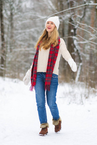 穿着冬衣的年轻快乐的女人走在雪林里