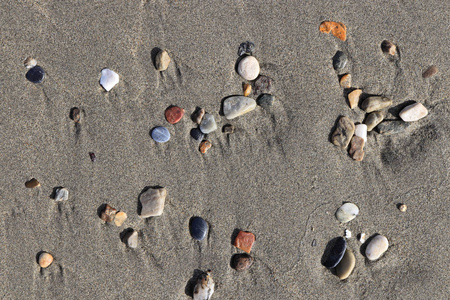 稀有卵石背景。 湿沙上有污渍的不同石头。 海滩美女背景。