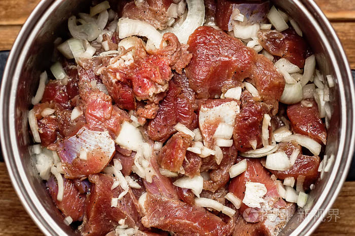 腌制肉片与洋葱在平底锅在木制背景. 烤肉用生肉的准备.