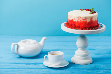 蛋糕装饰在白色杯子和茶壶附近的红色醋栗上