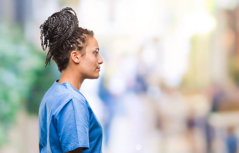 年轻的辫子非裔美国女孩专业护士在孤立的背景下，看着侧面放松的轮廓，自然的脸，自信的微笑。