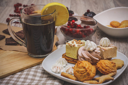 柠檬茶芝麻饼干在一个白色的碗松饼装饰巧克力，一碗红色浆果和一盘糖果是在一个轻木桌面。 节日糕点的组成。