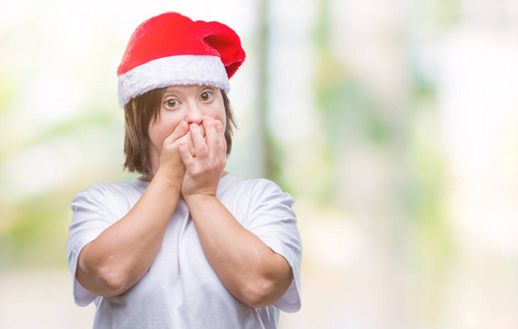 年轻的成年妇女患有唐氏综合症，戴着圣诞帽，在孤立的背景下震惊地用手捂住嘴，因为错误。 秘密概念。