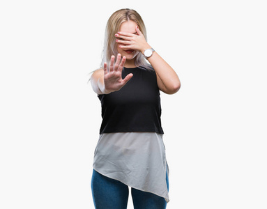 尴尬女年轻的金发女人在孤立的背景上用手遮住眼睛,用悲伤和恐惧的