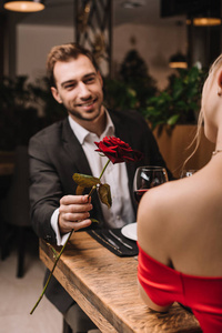 红玫瑰在快乐男人手中的选择性焦点在餐馆看女朋友
