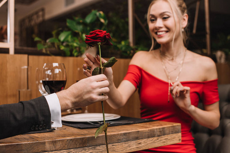 红玫瑰在男人手中的选择性聚焦背景下幸福的女友