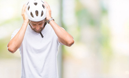 英俊的西班牙裔骑自行车的人戴着安全帽，在孤立的背景下，因为疼痛和偏头痛而感到头痛绝望和压力。 手放在头上。