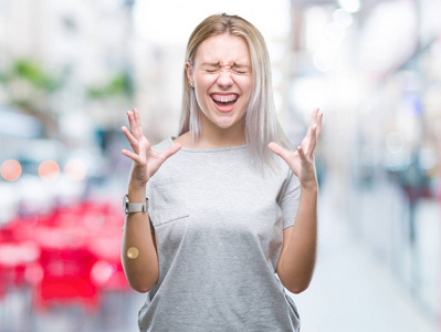 年轻的金发女人在孤立的背景下庆祝疯狂和疯狂的成功，举起手臂和闭上眼睛尖叫兴奋。 赢家概念