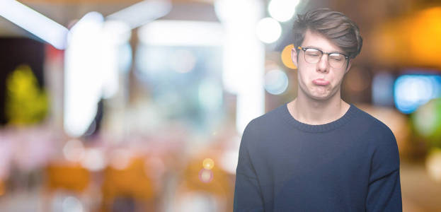 年轻的帅哥戴着眼镜，在孤立的背景下沮丧和担心痛苦，哭泣，愤怒和害怕。 悲伤的表情。