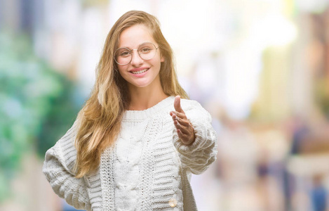 太阳年轻漂亮的金发女人穿着冬季毛衣和太阳镜,在孤立的背景上微笑