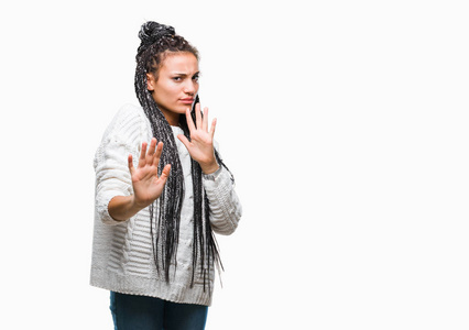 年轻的辫子非洲裔美国女孩穿着毛衣，在孤立的背景下，厌恶的表情，不高兴和恐惧的做厌恶的脸，因为厌恶的反应。 举起双手。 令人讨厌的