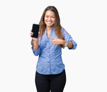 年轻漂亮的黑发商务女性在孤立的背景下显示智能手机屏幕，非常高兴地用手和手指指着。