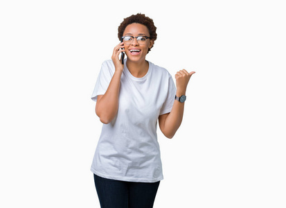 年轻的非洲裔美国妇女在电话中交谈，在孤立的背景下，指着并用拇指向侧面展示，脸上洋溢着幸福的笑容